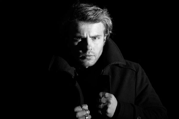 Black and White portrait of a man wearing a black coat interpreting a detective from the Sin City photo session